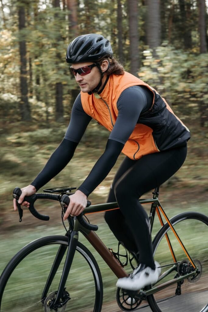 Cyclist in activewear biking through a lush forest trail, enjoying outdoor recreation.